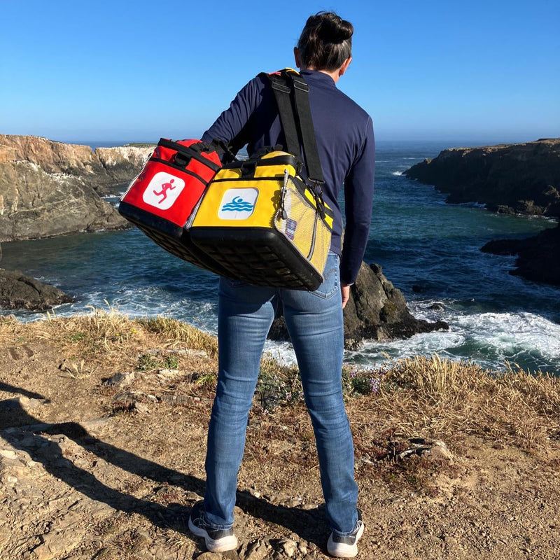 A woman with a yellow and red KitBrix transition bag, ready for adventure, traveling from the sea to the mountains.